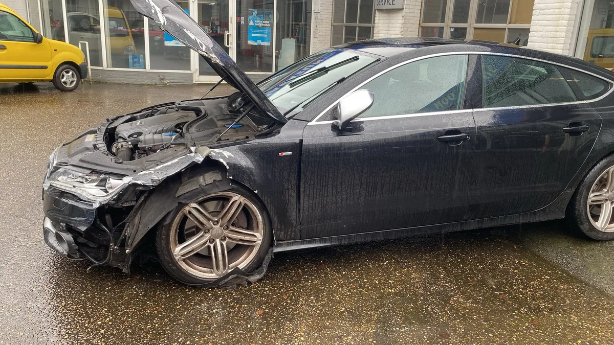 Donkere Audi A7 S-line met frontschade en open motorkap