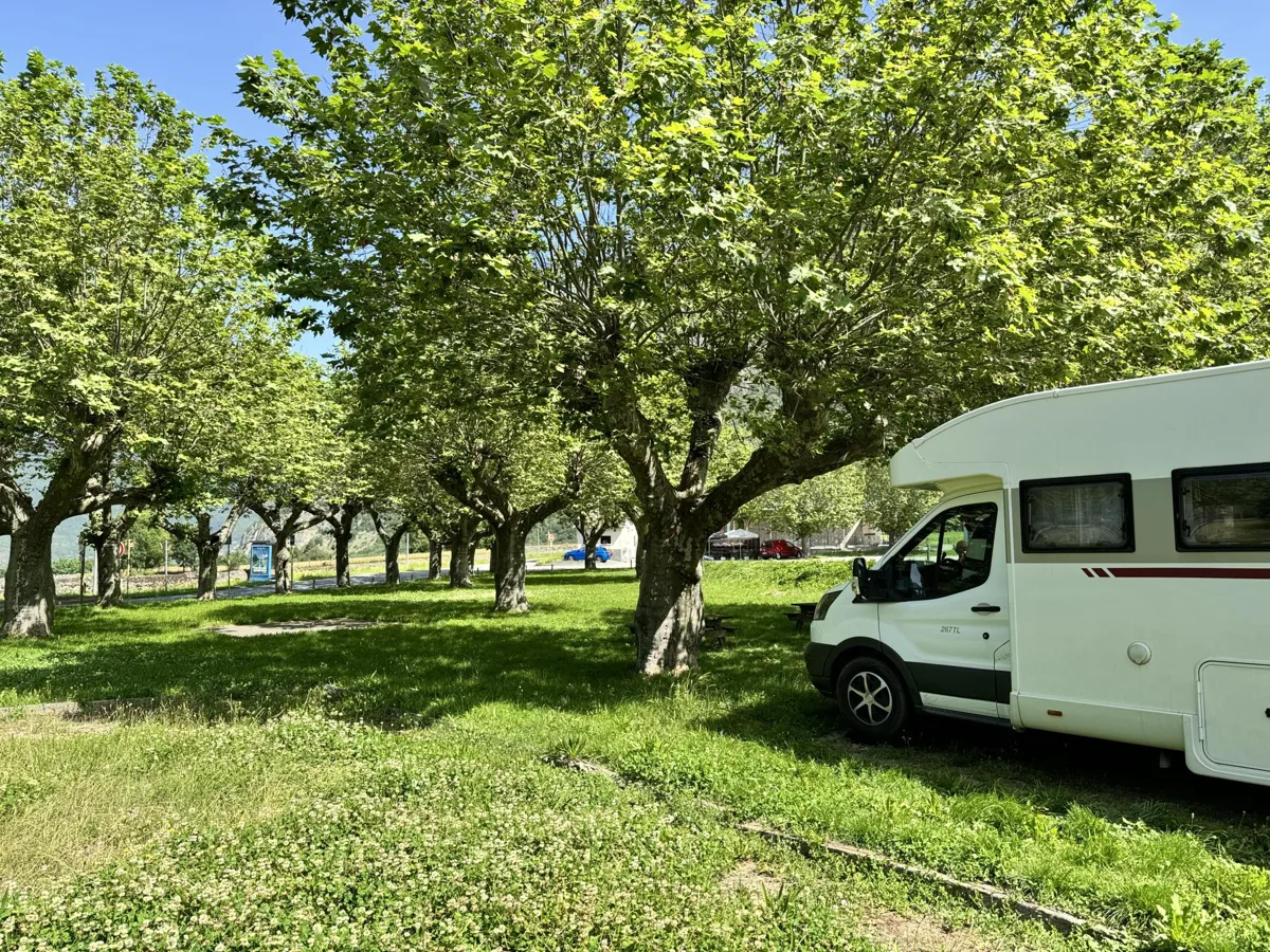 Witte camper geparkeerd onder de bomen op een camperplaats