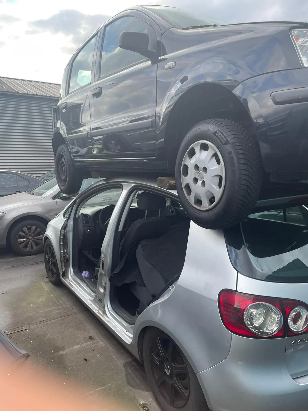 Gestapelde auto's op een autosloperij met een VW bus bovenop