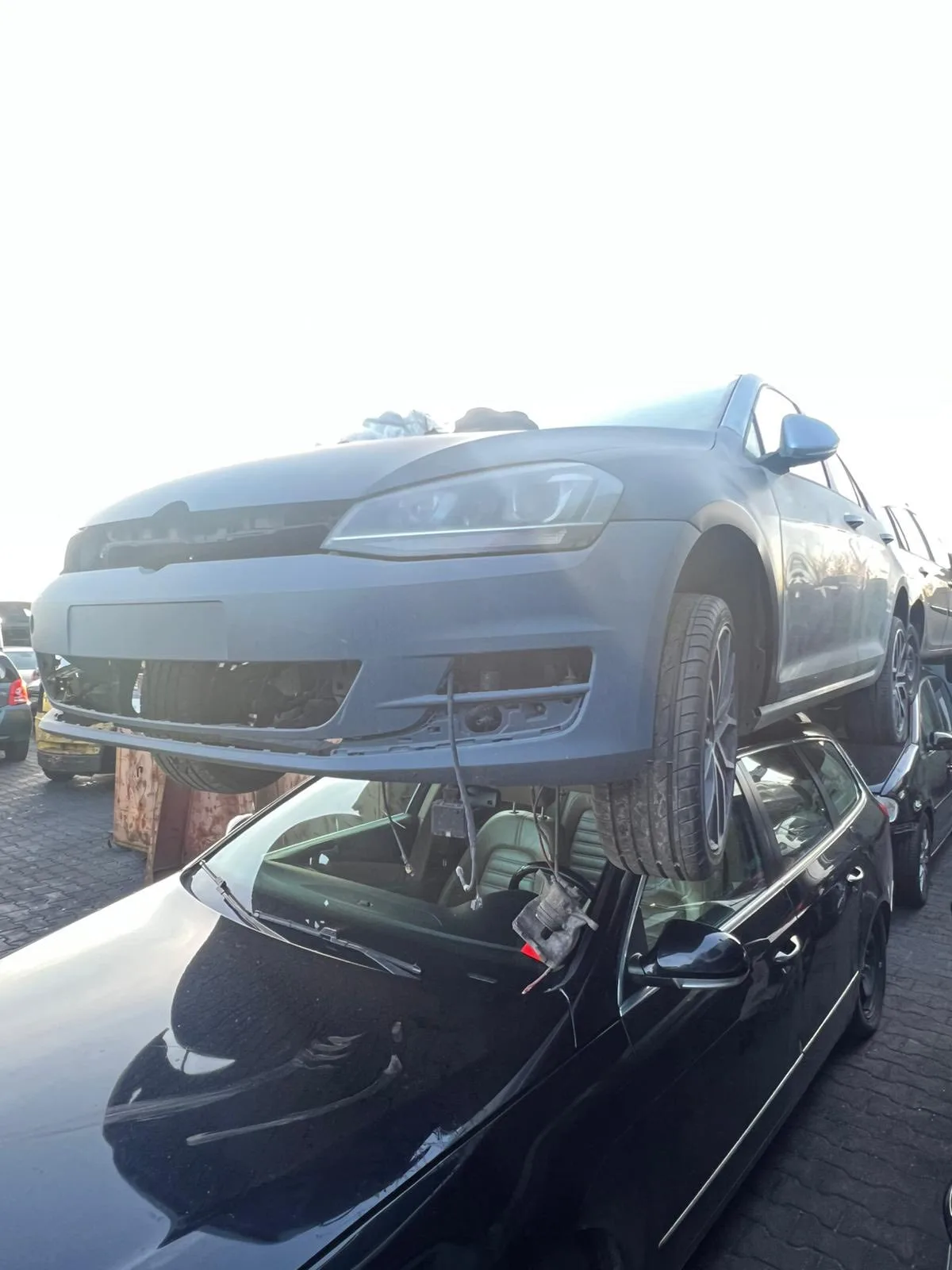 Grijze Volkswagen Golf gestapeld op een andere auto bij de sloperij